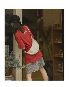 Close-up of a beige nylon crescent crossbody bag worn by a model in casual style