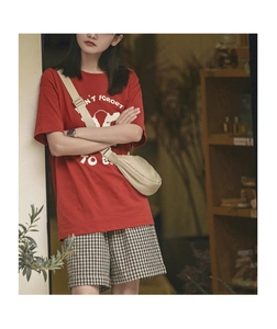 Detail of red cotton T-shirt featuring graphic print and minimalist beige crossbody bag