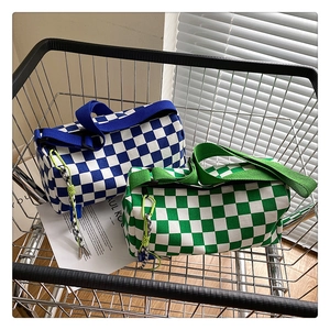 Sacs cylindriques à damier bleu et vert avec de larges bandoulières dans un chariot