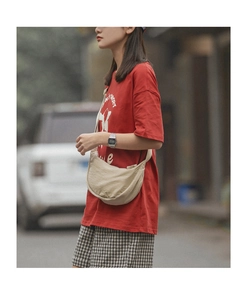 Detail of a beige crescent nylon crossbody bag worn by a model in casual street style