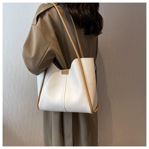 Detail of minimalist tote bag with contrast brown straps worn on a trench coat