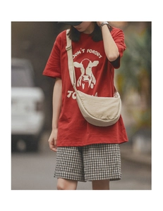 Beige nylon crescent crossbody bag styled with a red graphic tee and casual shorts