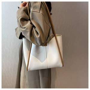 Minimalist white leather tote bag with brown handles worn by model in green trench coat