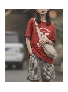 Close-up of a beige nylon crescent crossbody bag paired with a red graphic t-shirt