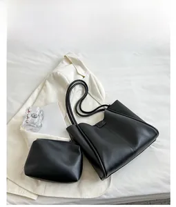 Detail view of a black tote bag and matching pouch on a white blazer for a work setting
