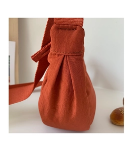 Detailed close-up of rust red nylon crossbody bag showing pleated texture and stitching
