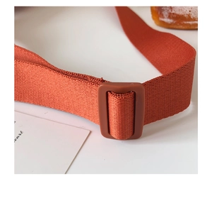 Detailed macro view of orange nylon shoulder strap with matte adjustable buckle for waist bag