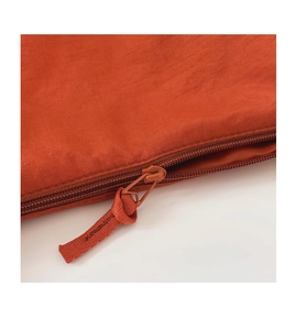 Detail of orange nylon shoulder bag featuring a matching zipper and woven rope puller