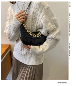 Detail der schwarzen Hobo-Tasche mit Krokodilprägung und goldener Kette am Model