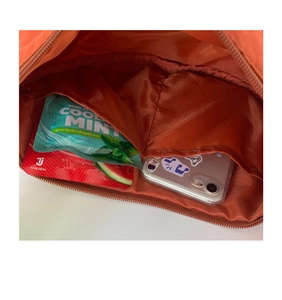 Internal view of the orange nylon crossbody bag showing two open inner slip pockets