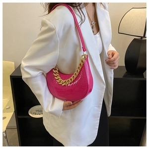 Rosa Schultertasche mit Krokodilmuster und Goldkette über einem weißen Blazer