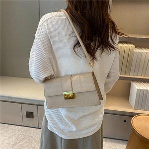Chic cream crocodile pattern crossbody bag with golden lock shown on shoulder