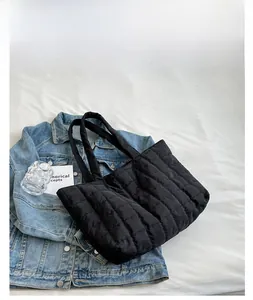 Detail of black quilted puffer tote bag on fabric with denim jacket and accessories