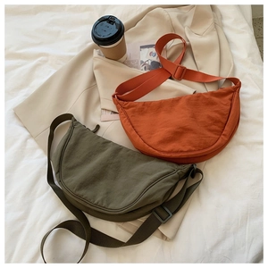 Detailed top view of olive green and brick red nylon crescent bags on casual fabric