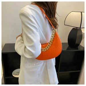 Orangefarbene Schultertasche mit Krokodilprägung und goldener Kette in Schulteransicht