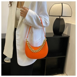 Seitenansicht der orangefarbenen Umhängetasche mit Krokoprägung und goldener Kette
