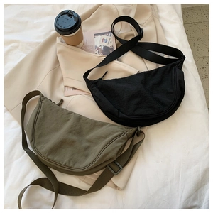 Flat lay of black and olive nylon crescent crossbody bags with adjustable straps
