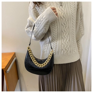 Schultertasche mit Krokodilprägung und goldener Kette getragen von einem Modell in Nahaufnahme