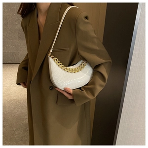 Detailansicht der weißen Schultertasche mit Kroko-Prägung und Goldkette an einem Model