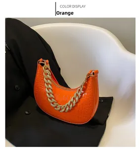 Detailansicht der orangefarbenen Umhängetasche mit Krokoprägung und dicker goldener Kette