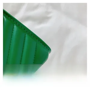 Detailed macro view of green leather handbag featuring classic V-shaped quilted stitching