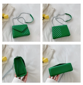 Detail view of green V-quilted faux leather crossbody bag with silver chain strap