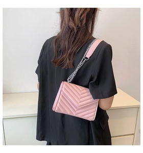 Pink quilted chevron leather bag detail with silver chain strap on a black outfit