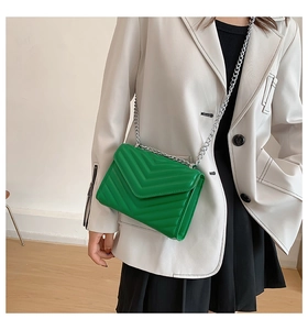 Detail of bright green quilted PU leather crossbody bag with silver metal chain strap