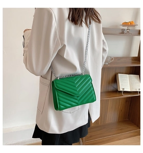 Model view showing the scale of a bright green V-quilted crossbody bag with silver chain