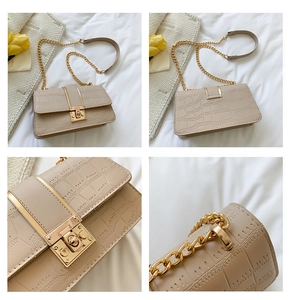 Detail van beige handtas met krokodillenpatroon, gouden draaislot en kettingriem