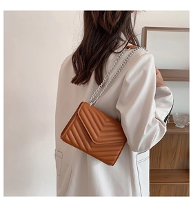 Detailed view of brown chevron quilted shoulder bag with silver chain strap and leather pad