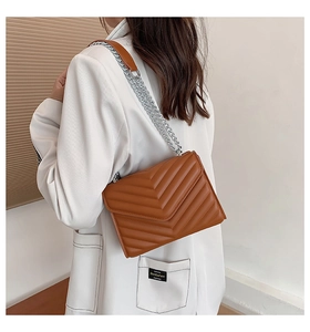 Close-up of brown V-quilted crossbody bag with silver chain strap and leather shoulder pad