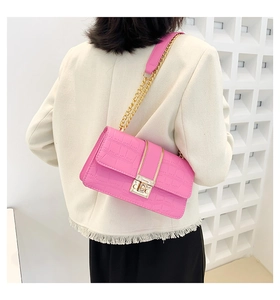 Detail of pink crocodile pattern shoulder bag with gold chain strap on a white tweed jacket