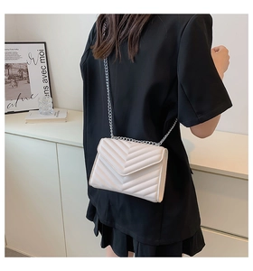 Close-up of cream quilted crossbody bag with chevron stitching and silver chain strap