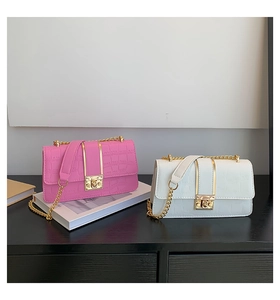 Detail of pink and white crocodile-patterned crossbody bags with gold metal clasps