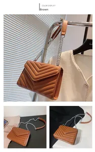 Detail of brown quilted crossbody bag with V-shaped stitching and chain strap