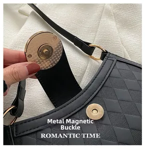 Vue détaillée de la boucle magnétique dorée sur un sac bandoulière noir en cuir matelassé