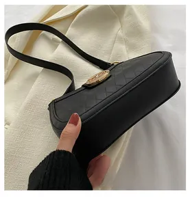 Détail du sac bandoulière matelassé noir avec ornement en métal doré sur fond de veste
