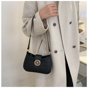 Détail d'un sac noir avec emblème de gouvernail doré et texture géométrique en relief