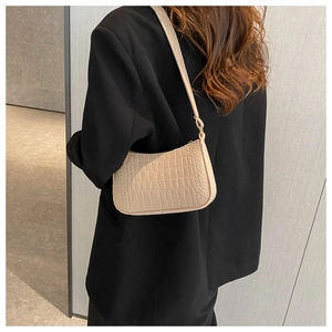Model wearing a beige crocodile pattern crescent shoulder bag with black blazer