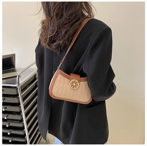 Détail du sac beige matelassé avec boucle nautique dorée et finitions en cuir marron