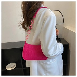 Fuchsia shoulder bag with crocodile texture and unique large link strap on white blazer