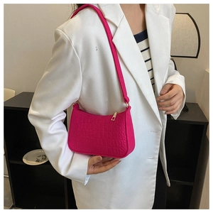 Close-up of fuchsia crocodile pattern felt shoulder bag with gold zipper detail