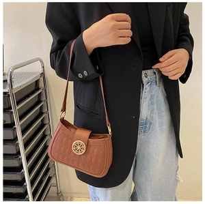 Sac sous le bras matelassé marron avec boucle nautique dorée porté par un mannequin