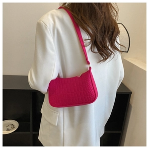 Detail of hot pink crocodile embossed baguette bag with metallic gold zipper on white suit