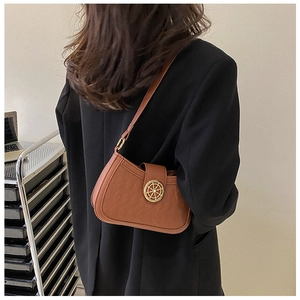 Gros plan du sac bandoulière matelassé marron avec boucle gouvernail sur un costume