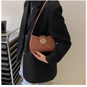 Détail du sac rétro marron montrant la texture matelassée et le fermoir en métal doré sur blazer