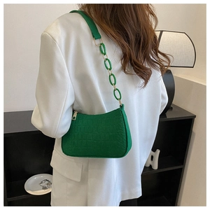 Detail of green crocodile embossed shoulder bag featuring acrylic chain on white blazer