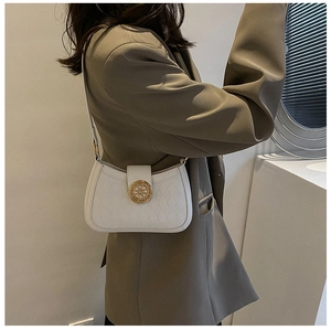 Détail du sac sous l'aisselle blanc matelassé avec boucle dorée sur blazer marron