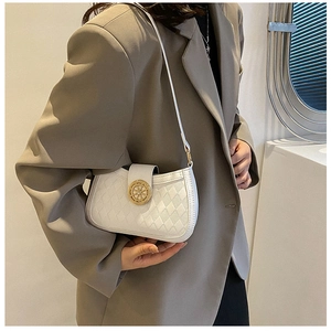Détail du sac sous le bras matelassé blanc avec boucle dorée sur blazer gris